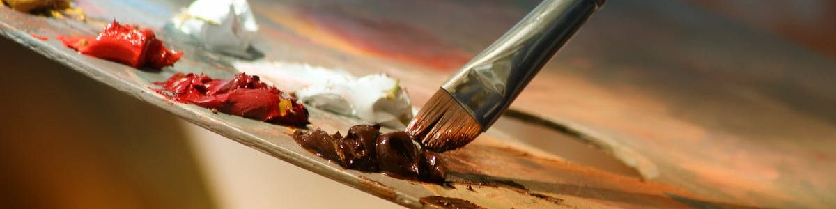 Vibrant artist palette with paint and brush creating colorful artwork.